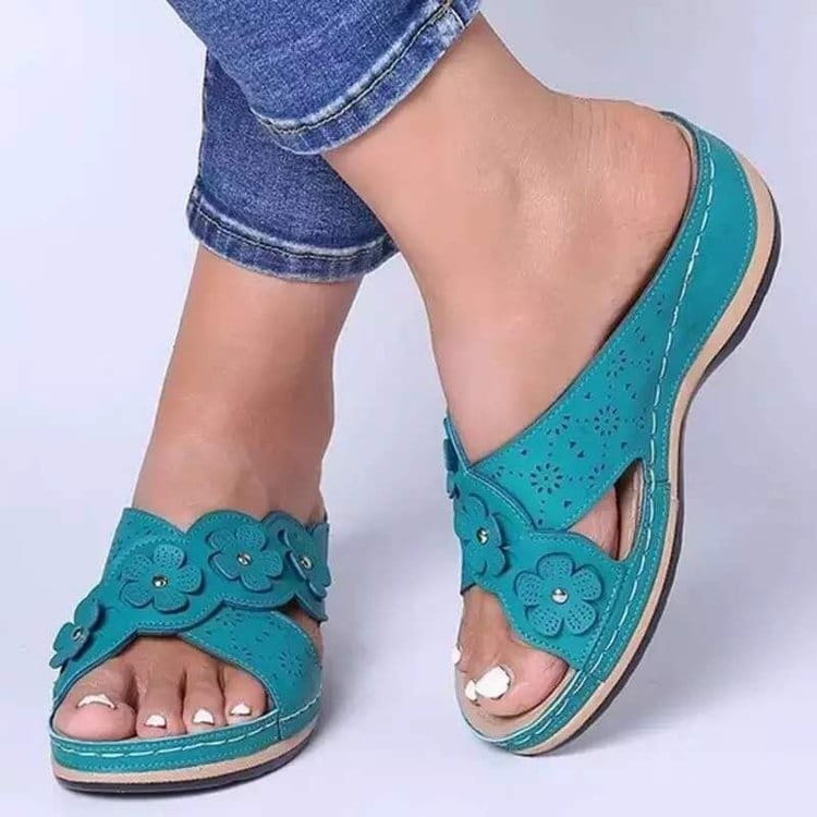 Des mules compensées en cuir à motif floral rétro vert canard, avec des lanières perforées et des appliqués floraux décoratifs.