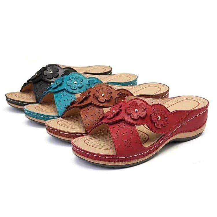 Des mules en cuir à motif floral rouge, avec des détails perforés et un talon compensé, pour une tenue d’été rétro élégante.
