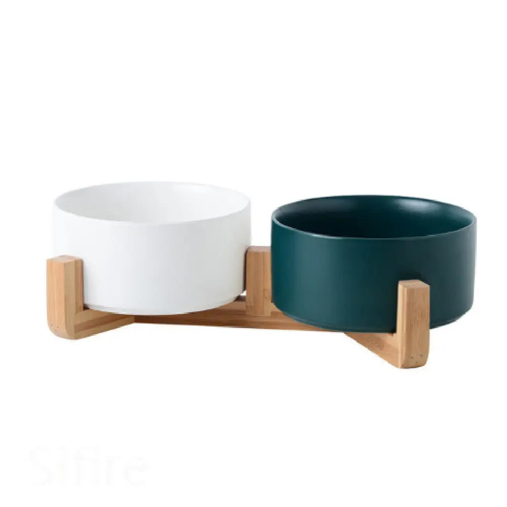 Modern pet feeding station with ceramic double pet bowls in white and deep teal mounted on a light wood stand.