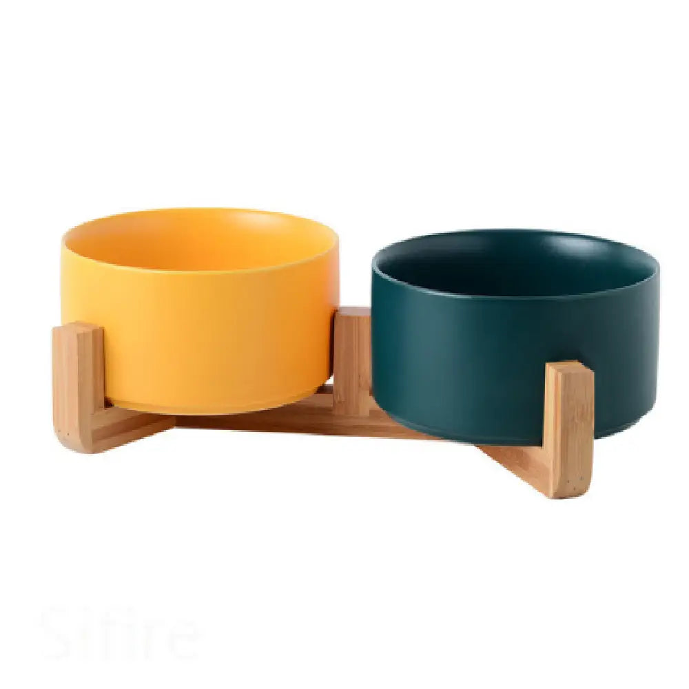 A sleek ceramic double pet bowl with one yellow and one teal ceramic bowl mounted on a minimalist wooden stand.