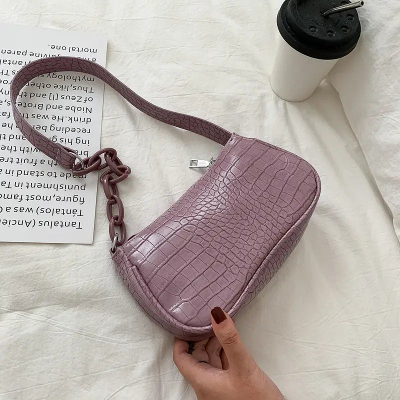 A lavender croc embossed chain shoulder bag for women featuring crocodile-textured material and a chunky chain strap.