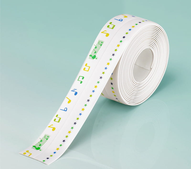Un rouleau de ruban adhésif d’étanchéité pour cuisine en PVC blanc, imperméable et anti-moisissure, avec des notes de musique et des étoiles colorées en vert, jaune, bleu et noir.