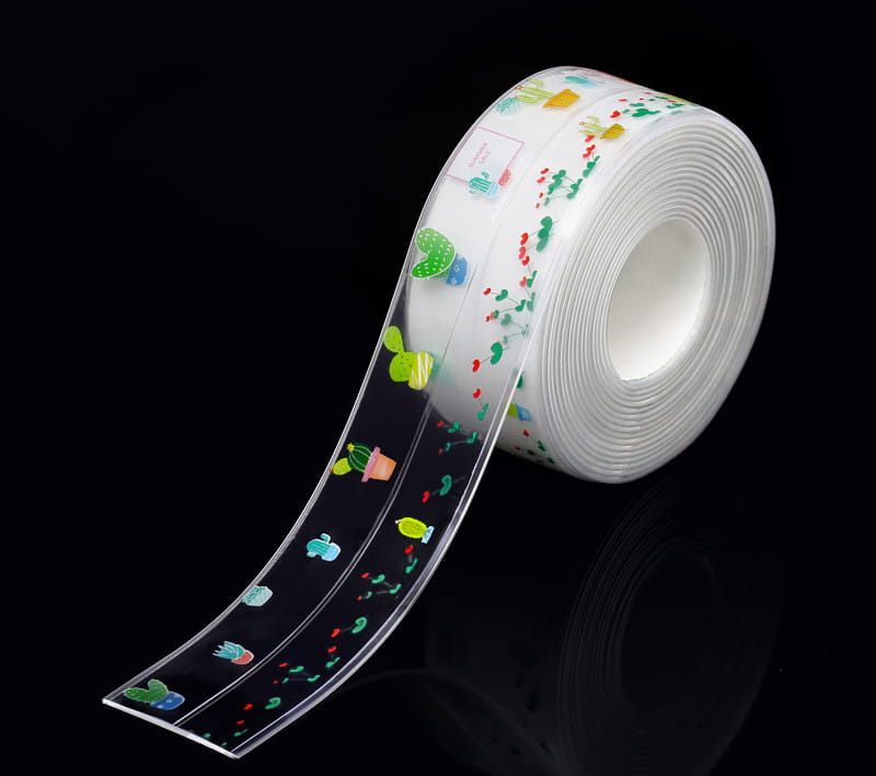Un rouleau de ruban adhésif d’étanchéité pour cuisine en PVC transparent, anti-moisissure, présentant des cactus et des motifs de plantes de dessin animé colorés en vert, jaune, rouge et bleu, à des fins de scellement imperméable.