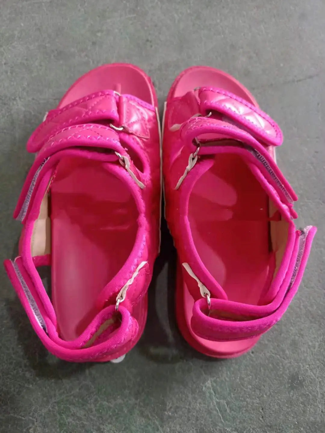 Bright pink children’s velcro sandals with glossy finish suitable for beach wear with quilted platform soles.