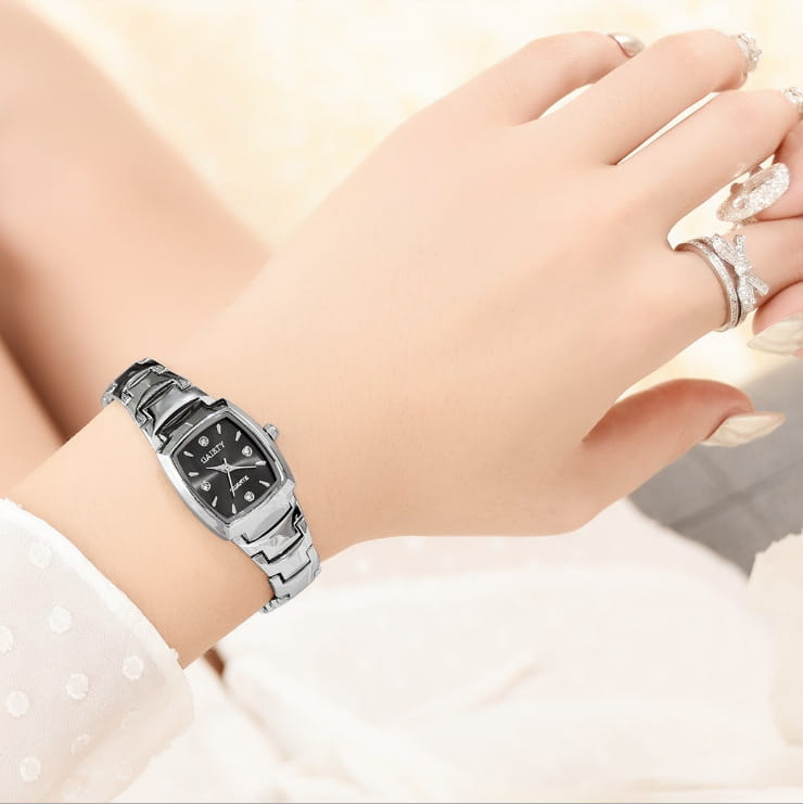 Montre rectangulaire en quartz argenté avec cadran noir et des accents en forme de diamants sur les index des heures.