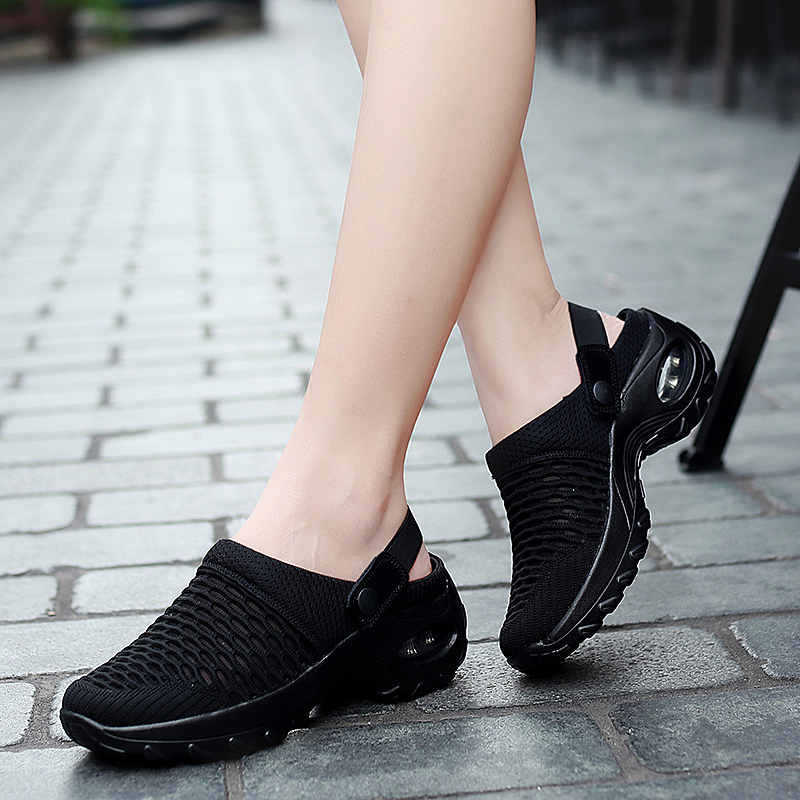 Black mesh athletic sandals with a thick cushioned sole and adjustable strap designed for breathable height increasing comfort.