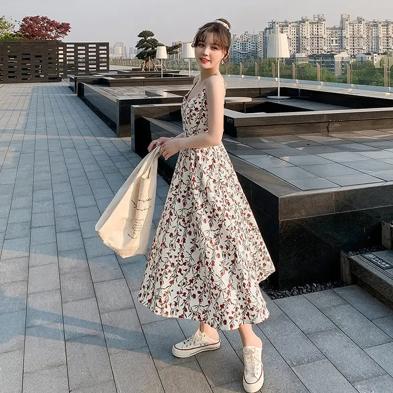 A flowing off-white floral print halter midi dress for women features a delicate pattern of red and green floral motifs.