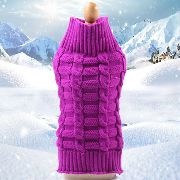 Un pull pour chien en cachemire torsadé bleu clair magenta éclatant, à col roulé haut, avec un motif de torsades en câble tricoté complexe, présenté sur un mannequin en bois devant un paysage de montagne enneigé.