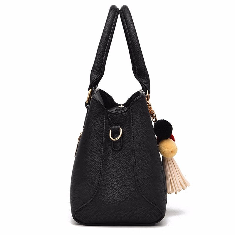 Luxury women handbags woven pu leather crossbody bag in black pebbled leather with gold-tone hardware and a decorative pom-pom tassel charm.