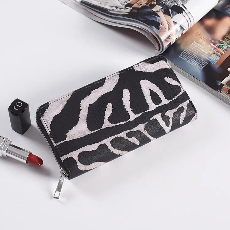 Schwarzes und weißes Zebrastreifen-Leder-Portemonnaie mit langem Reißverschluss für Damen mit einem silberfarbenen Reißverschluss.