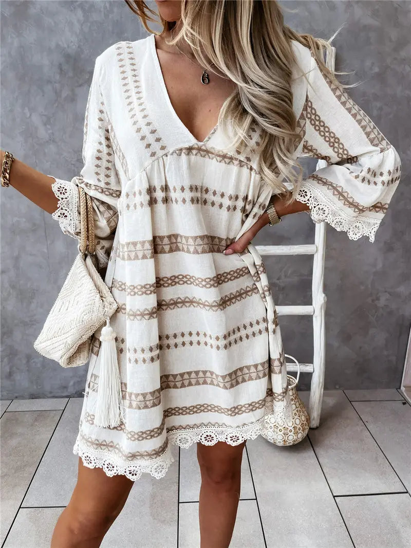 A flowing off-white boho mini dress with beige geometric patterns and delicate lace trim at the neckline sleeves and hem.