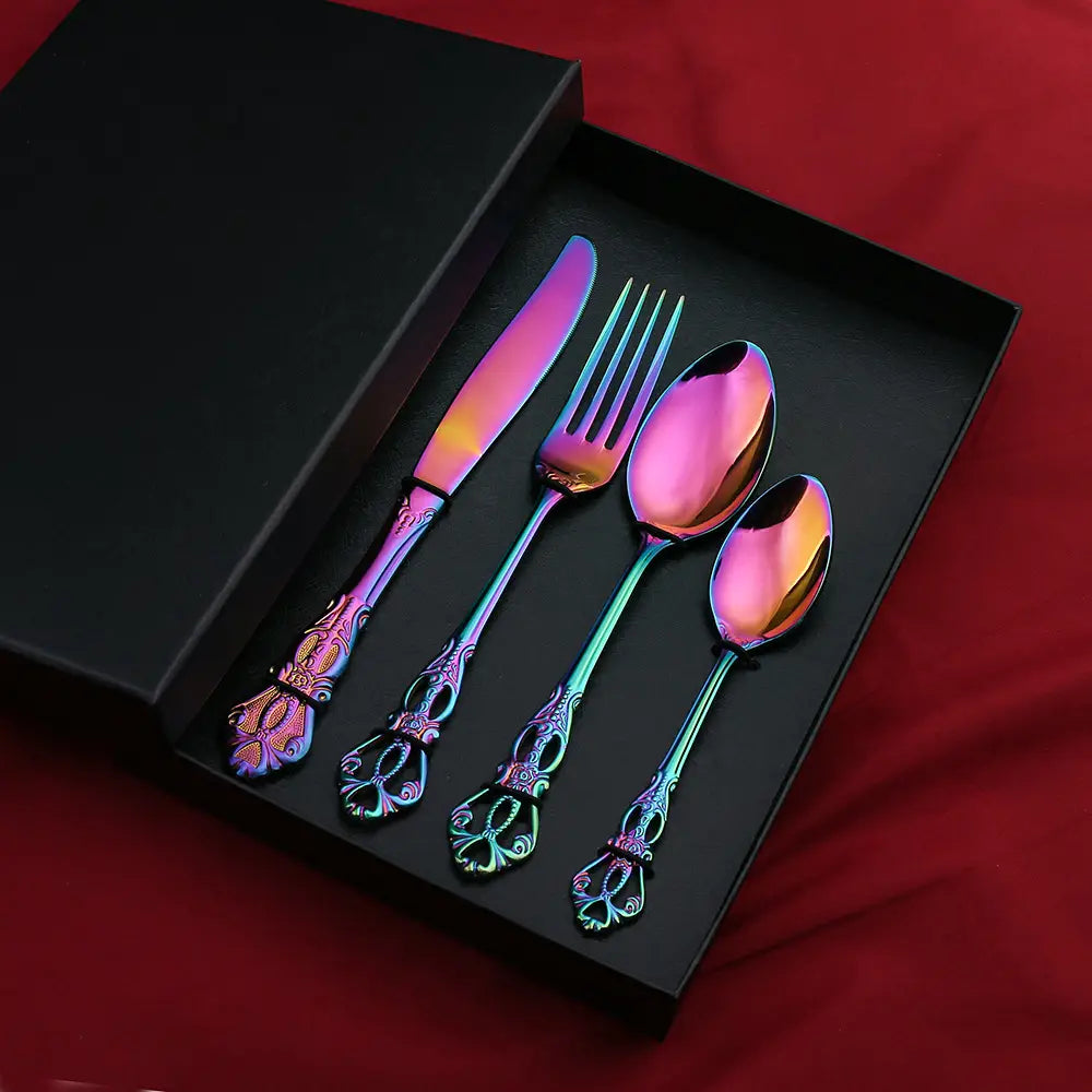 Un ensemble de couverts en acier inoxydable de la Cour Royale, avec une finition arc-en-ciel irisée et des poignées ornées au style vintage, présenté dans une boîte-cadeau noire.