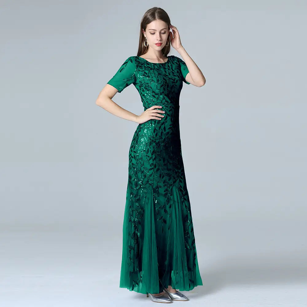 emerald green embroidered sequin mermaid evening gown with tulle skirt featuring sequined leaf patterns and a flowing skirt