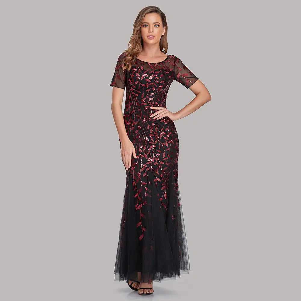 A black and burgundy embroidered sequin mermaid evening gown featuring sheer short sleeves and a tulle skirt.