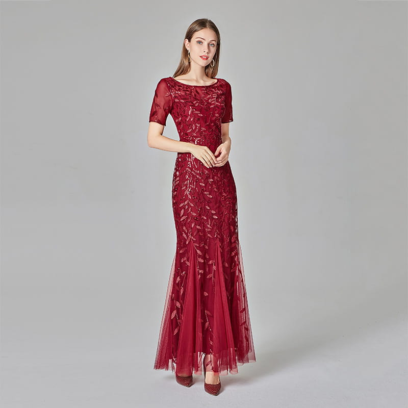 A deep red floor-length embroidered sequin mermaid evening gown with short lace sleeves and a tulle skirt.