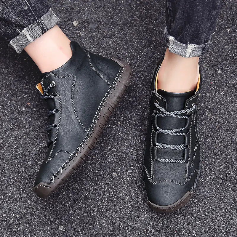 Black leather ankle boots with contrasting gray laces and visible hand stitched details in a vintage high top sneaker style.