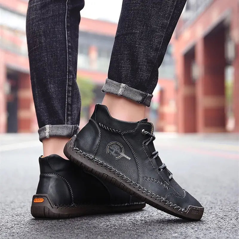 Black leather ankle boots with hand-stitched detailing and a subtle logo on the side designed as vintage high top sneakers.