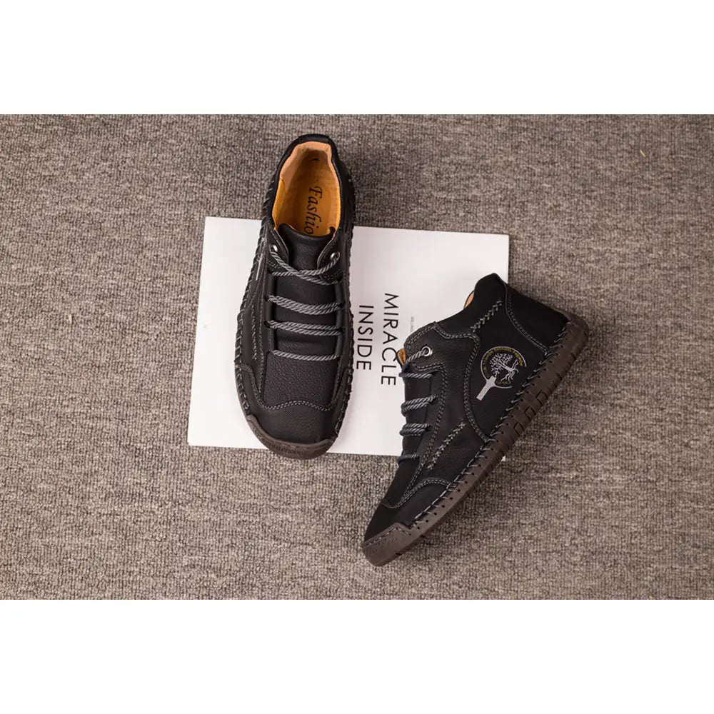 Leather boots hand stitched vintage high top sneakers in black leather with lace-up closure, textured upper, contrasting stitching, and a subtle circular logo on the side.