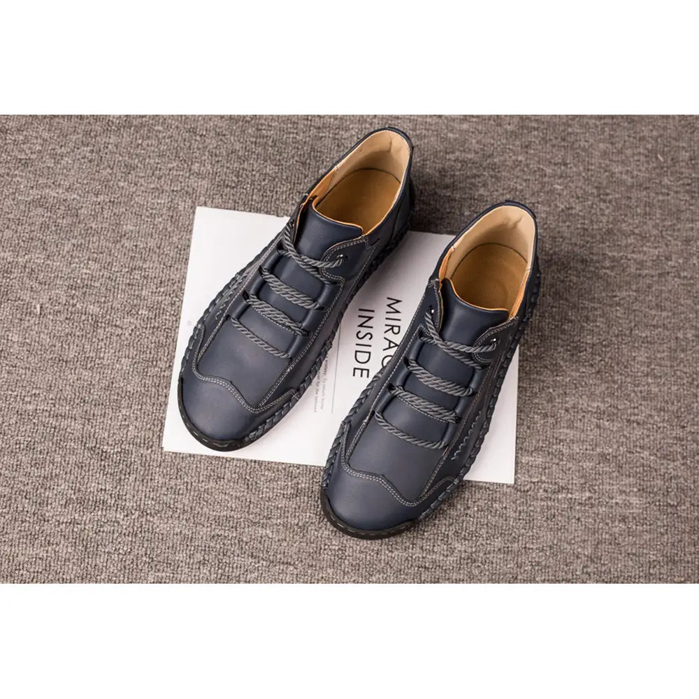 Dark blue leather hand stitched vintage high top sneakers with a textured woven pattern along the sides and toe area.