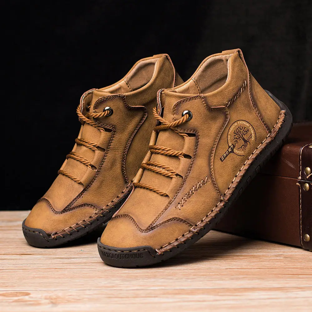 Tan leather ankle boots with brown laces and visible stitching featuring a circular tree emblem designed as hand stitched vintage high top sneakers.