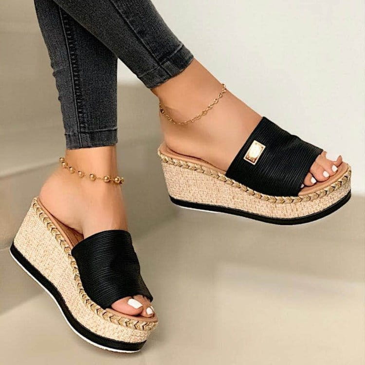Black espadrille wedge sandals with a woven straw sole and a gold-tone rectangular buckle featuring denim and metal accents.