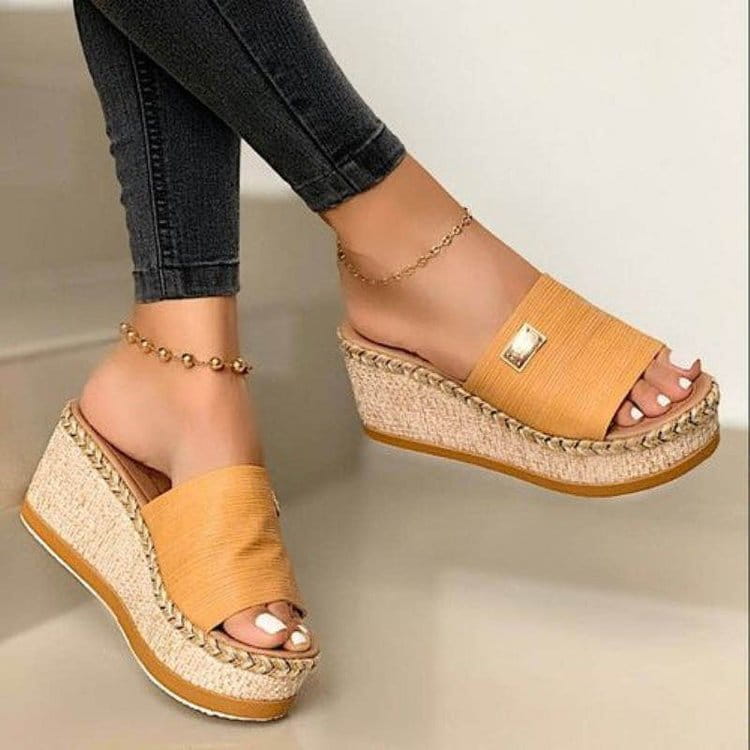 Tan espadrille wedge sandals with a braided rope sole and a gold-tone metal accent featuring denim and metal details.