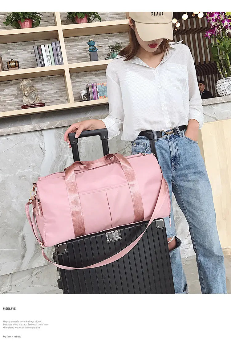 Rose gold nylon waterproof sports duffel bag in pink with metallic rose gold straps and a retractable handle designed for travel.