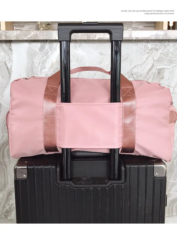 Pink nylon waterproof sports duffel bag with rose gold-toned webbing straps and a front pocket designed for travel
