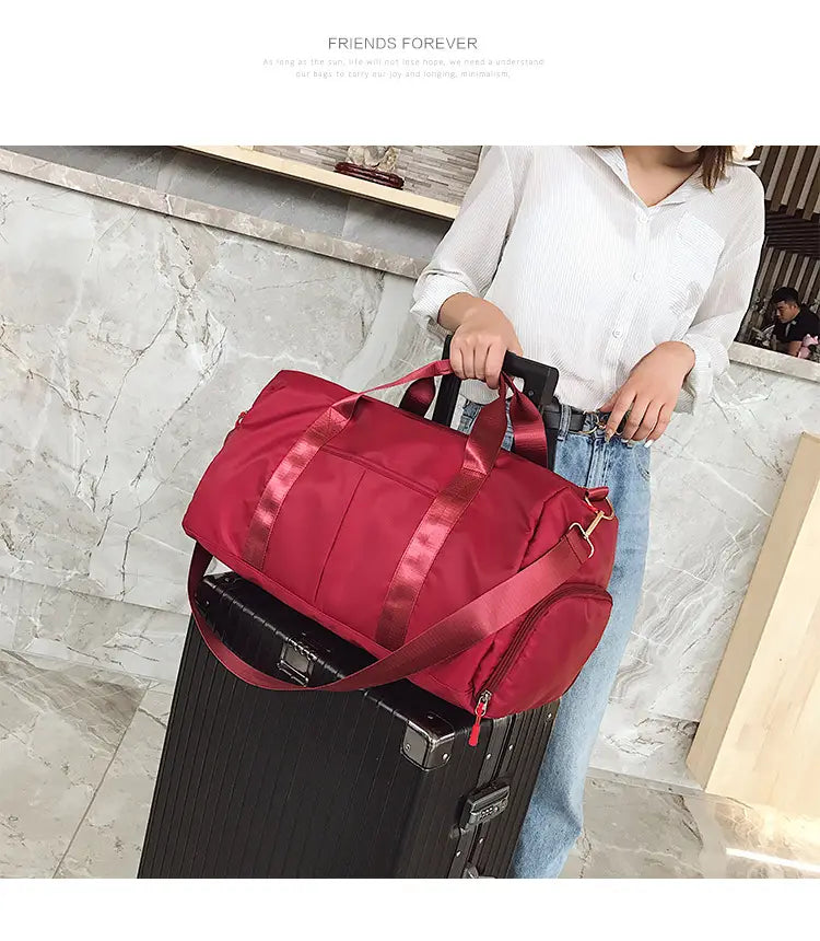 Red nylon sports duffel bag with satin-like straps and a front zippered pocket featuring a rose gold waterproof finish.