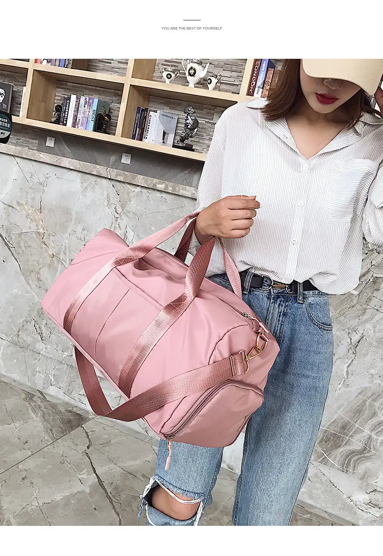 Pink nylon waterproof sports duffel bag with matching shoulder strap and gold-tone hardware.