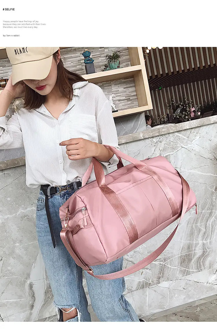 Pink nylon waterproof sports duffel bag with matching shoulder strap and reinforced handles.