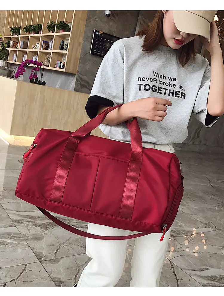 red nylon waterproof sports duffel bag with satin-like handles and detachable shoulder strap shown from the front.