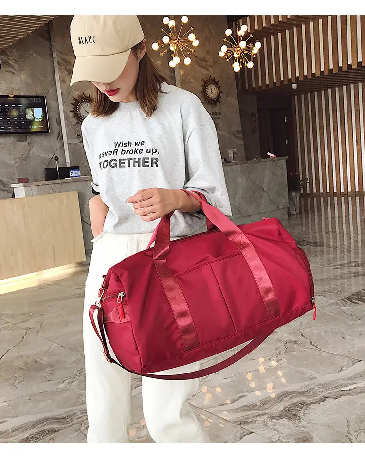 Red nylon duffel bag with satin-like straps and multiple zippered compartments designed for sports and travel use.