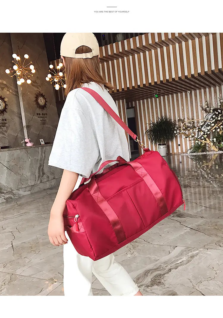 Red nylon sports duffel bag with rose gold waterproof finish, matching shoulder strap, and reinforced handles.