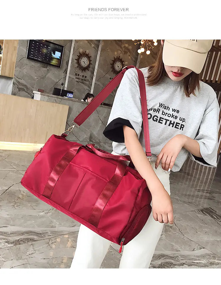 Rose gold nylon waterproof sports duffel bag in red with matching shoulder strap and reinforced side handles.