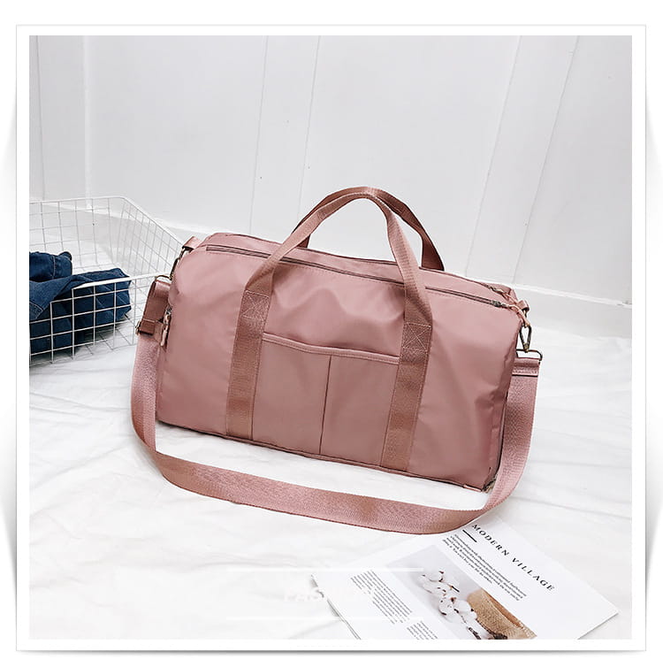 A sleek dusty rose-colored nylon waterproof sports duffel bag with a matching adjustable shoulder strap and front pocket.
