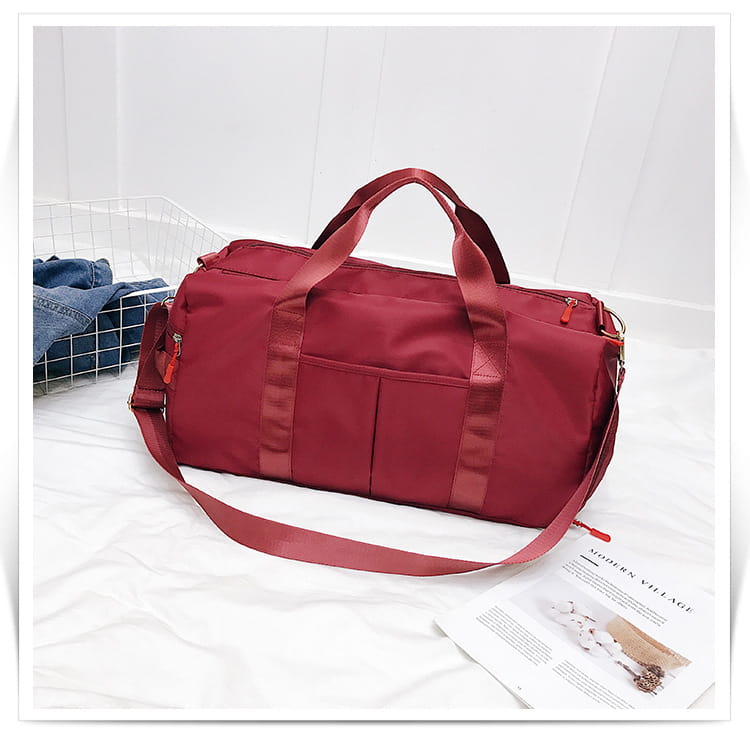 A maroon nylon rose gold nylon waterproof sports duffel bag with matching handles, a detachable shoulder strap, and multiple zippered compartments.