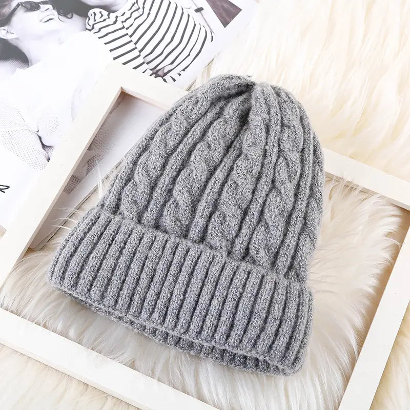 Gray cable knit beanie hat with a fleece lining and ribbed brim designed for winter warmth.