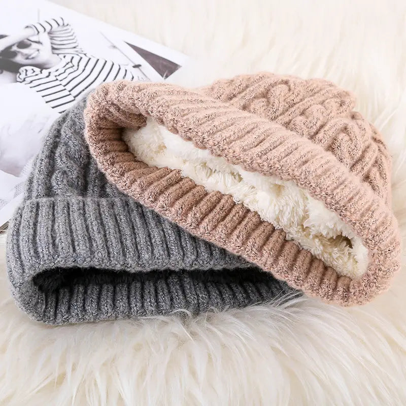 A cozy cable knit beanie hat in soft gray and beige with a plush white fleece lining designed for winter warmth.