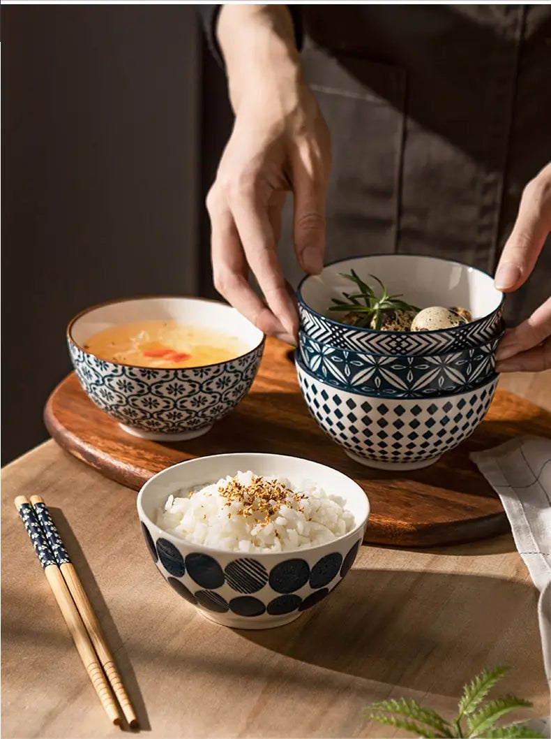three ceramic bowls from a japanese floral porcelain 5 piece set with blue and white geometric patterns holding rice soup and a herb garnished dish