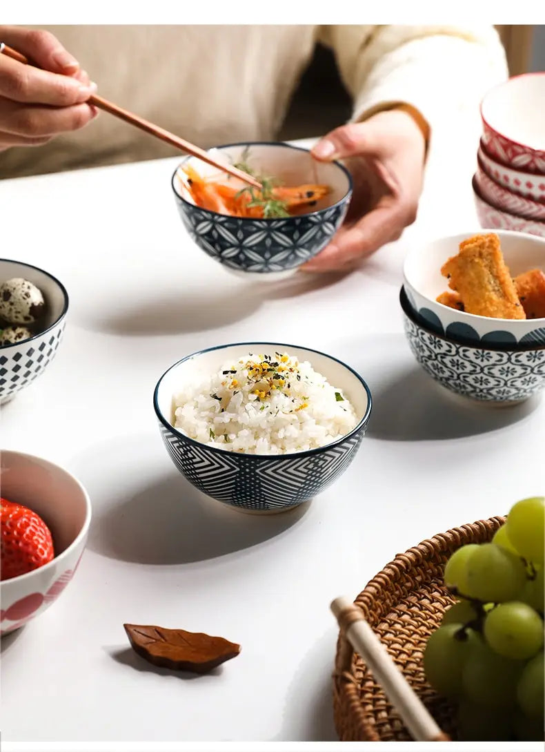 Ceramic bowl from a five piece Japanese floral porcelain set featuring a black and white geometric pattern and holding steamed rice topped with sesame seeds.