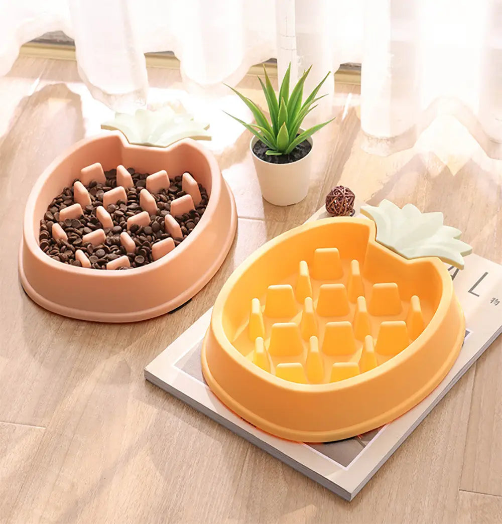 Dos cuencos para perros de alimentación lenta con forma de piña en color durazno y amarillo brillante, elaborados con plástico liso, con acentos de hoja moldeados para mascotas.