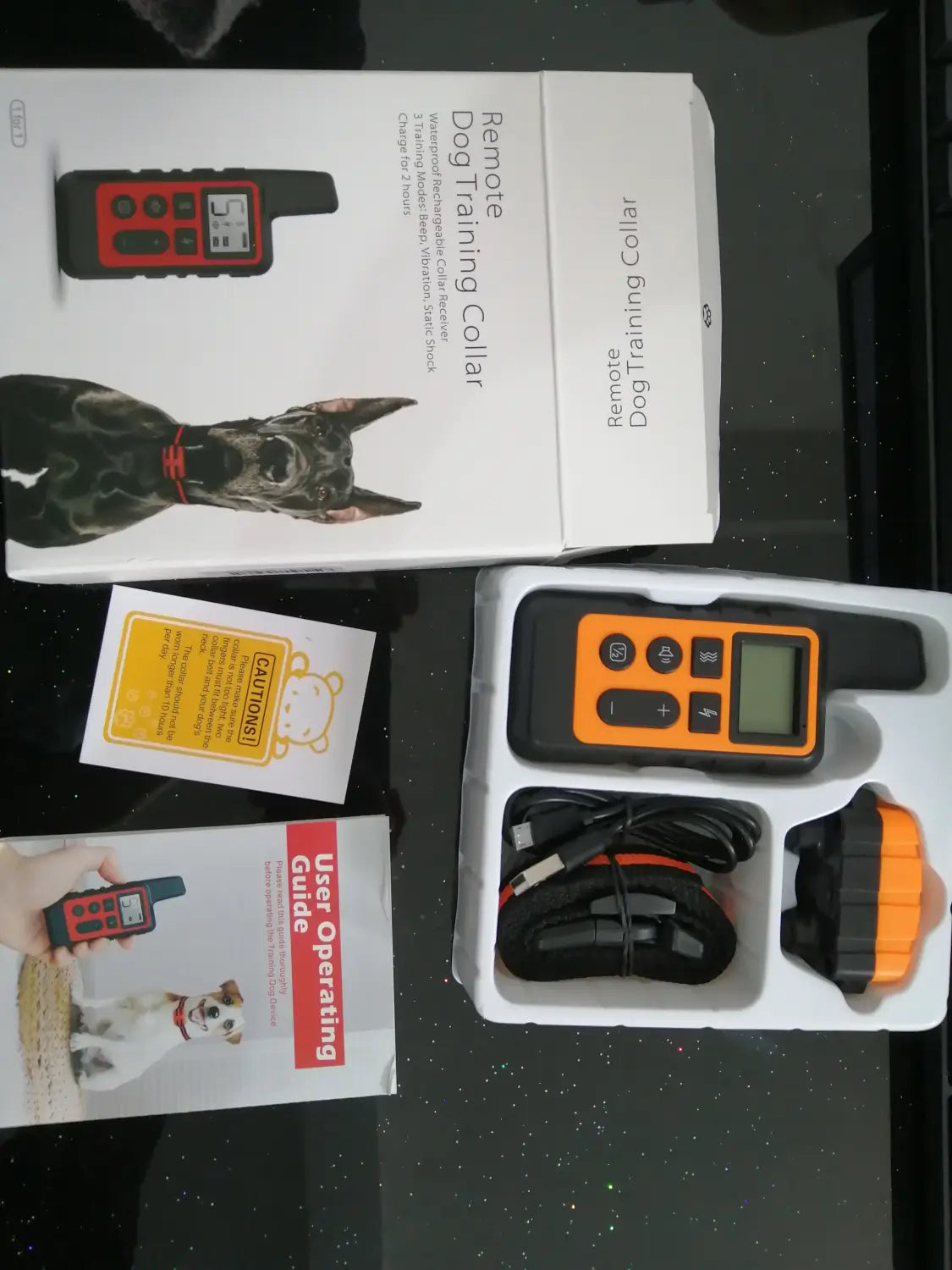 Orange and black dog training collar system with 500m waterproof remote includes handheld transmitter charging base and adjustable collar for effective training.
