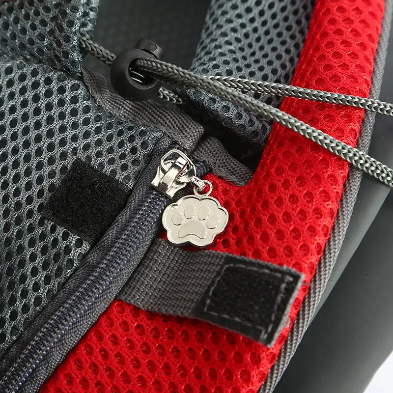 Silver paw print zipper pull on red and gray breathable mesh pet carrier backpack made of durable mesh material.