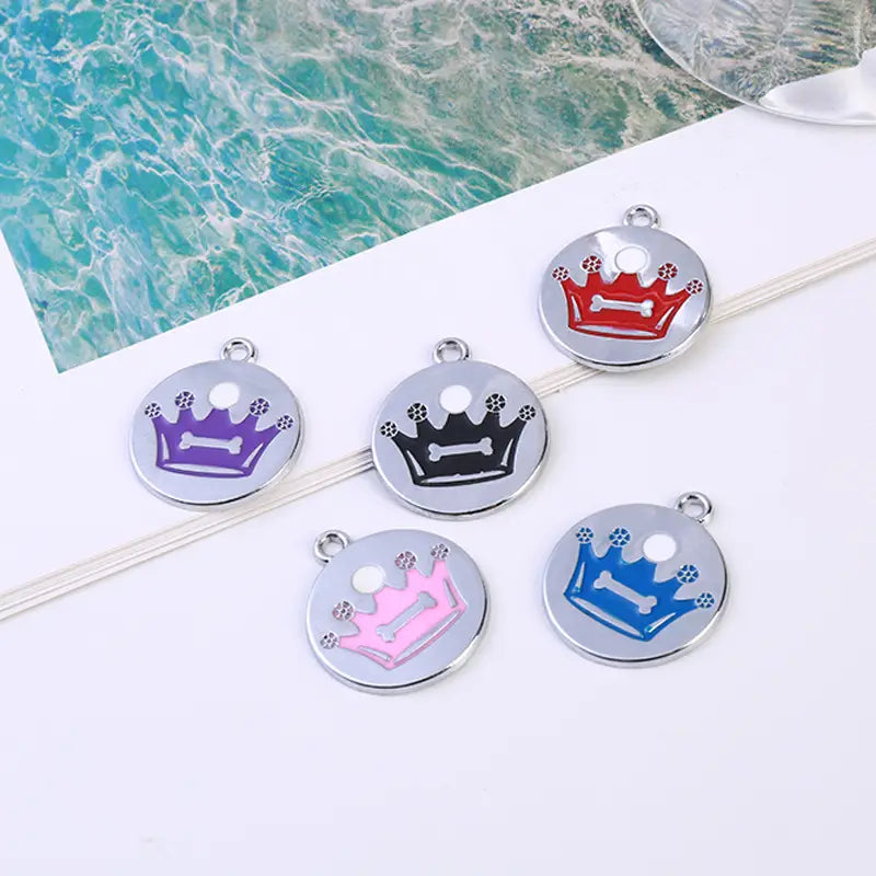 circular metal pet id tags with crown and bone designs in red, purple, black, pink, and blue enamel finishes shown in a crown enamel pet id tag 5 pack
