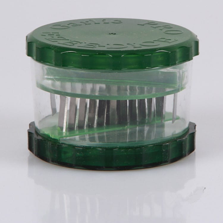 Green plastic garlic pro manual grinder and peeler kitchen tool with clear central chamber and metallic blades.
