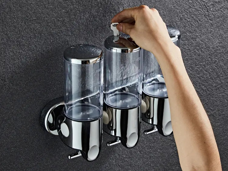Wall mounted soap dispenser chrome abs pump with a chrome finish and three transparent cylindrical chambers for soap and lotion.