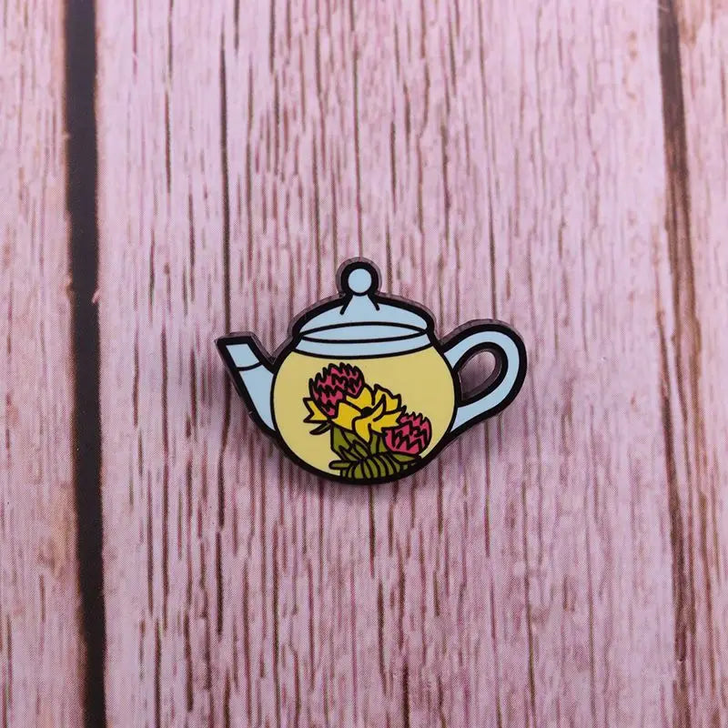 Yellow enamel cat witch teapot pin with pink and yellow floral design and light blue accents on lid and spout made of whimsical copper.