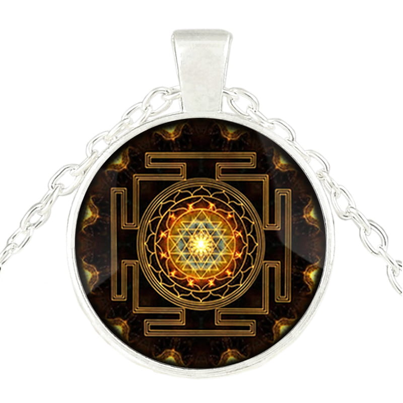 Silver-toned pendant necklace featuring a circular glass cabochon with an intricate golden sri yantra design on a dark background.