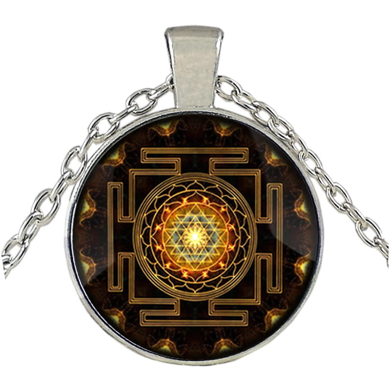 Silver-toned pendant necklace featuring a circular glass cabochon with an intricate golden sri yantra design on a dark background suspended from a matching silver chain.